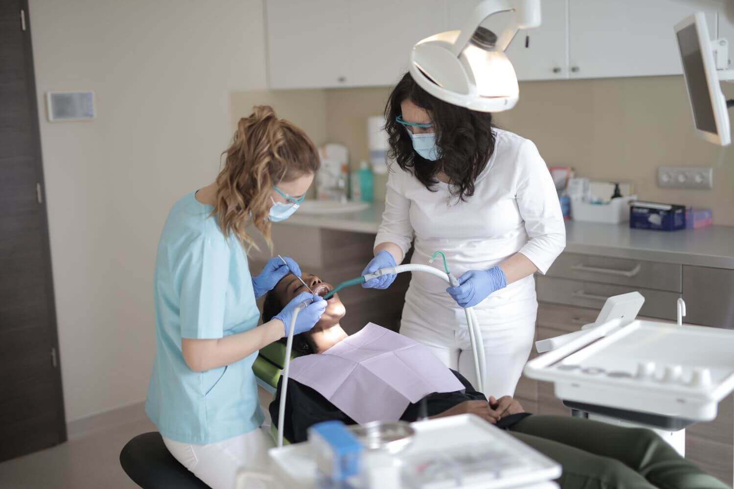 Odontoiatra e assistente al lavoro sulla poltrona con un paziente in studio