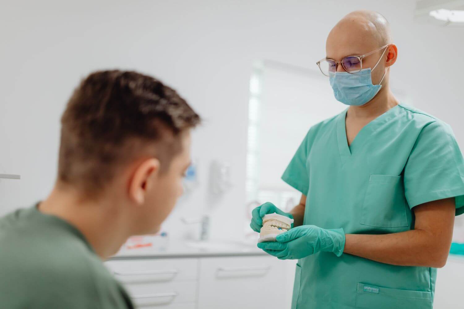 Odontoiatra spiega il piano di cura con un modello dentale a un paziente